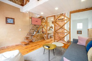 A modern interior with a staircase, a sofa, a coffee table, and a kitchen area. - GuestReady - Modern Duplex in Lisbon (Lisbon)