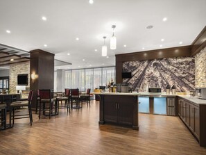 Une cuisine moderne avec un mur d’accent en pierre, un bar et un grand îlot central.