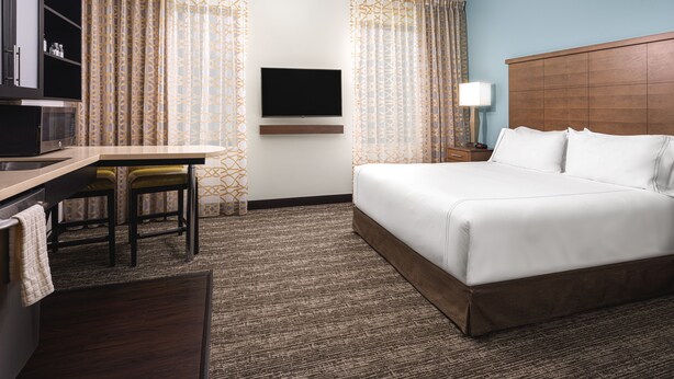A hotel room with a bed, a desk, a television, and a lamp. - Hearing Accessible Studio Suite w/ Free Breakfast (Seattle)