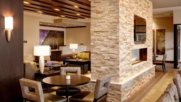 A modern interior with a stone accent wall, a fireplace, and a seating area with a round table and chairs. - Hearing Accessible Studio Suite w/ Free Breakfast (Seattle)