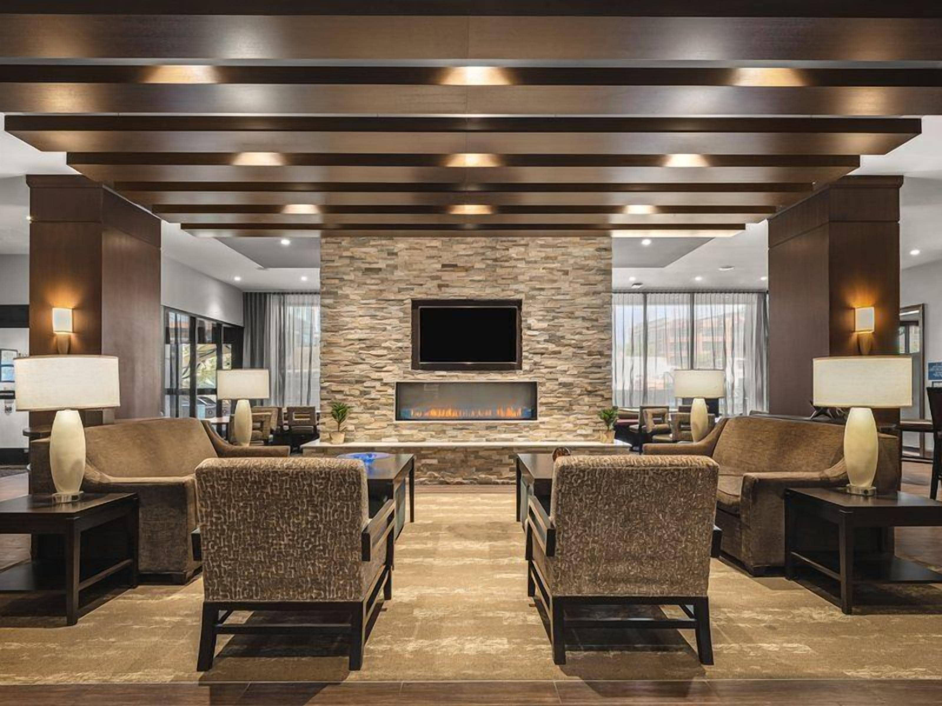 A lobby with a stone wall, a flat-screen TV, and two sofas.
