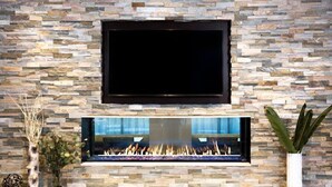 A stone wall with a flat-screen TV mounted above a fireplace. - Accessible Studio Suite w/ Tub + Free Breakfast! (Seattle)