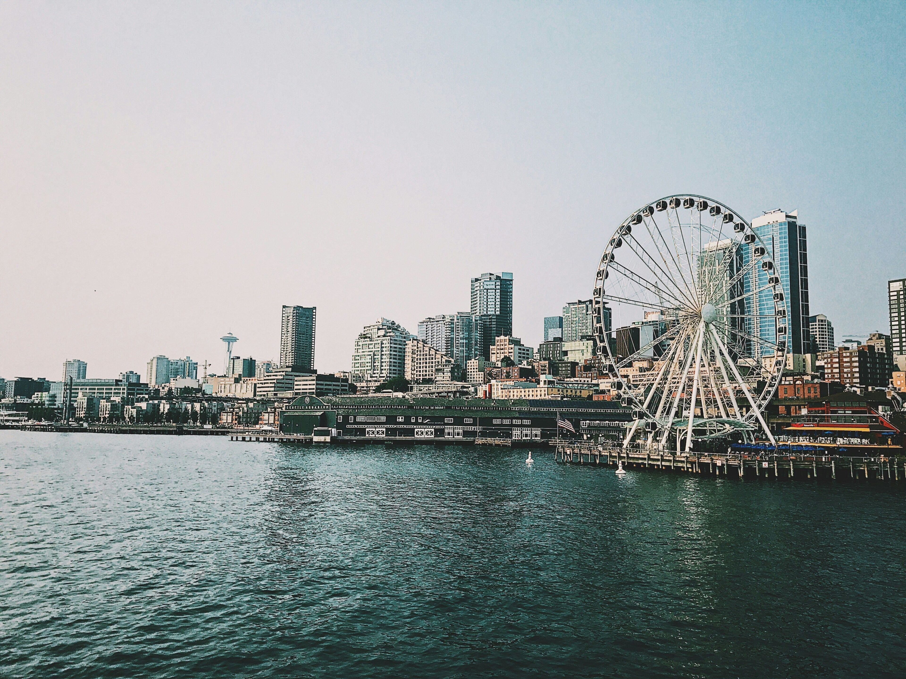 A waterfront cityscape with a prominent Ferris wheel and modern skyscrapers.