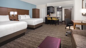 Une chambre d’hôtel avec deux lits, un bureau, une kitchenette et une salle de bain.
