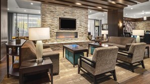 Un salon moderne avec un mur en pierre, une cheminée, un téléviseur à écran plat et des sièges confortables.