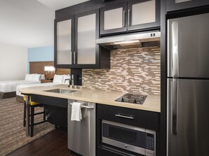 A modern kitchen with stainless steel appliances, a tiled backsplash, and a separate dining area with a bar stool.