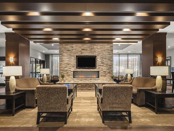 A lobby with a stone wall, a flat-screen TV, and two sofas.