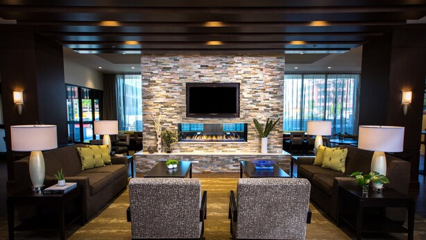 A modern living room with a stone fireplace, comfortable seating, and a flat-screen TV.
