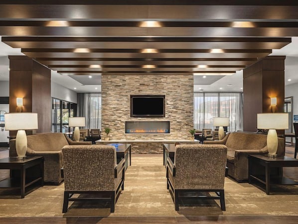 A lobby with a stone wall, a flat-screen TV, and two sofas.