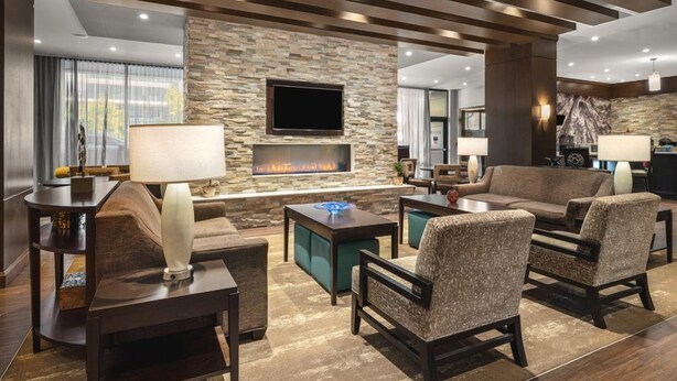 Una sala de estar moderna con pared de piedra, chimenea, televisor de pantalla plana y asientos cómodos.
