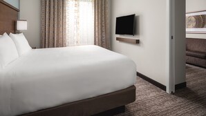 Habitación de hotel con una cama grande, un televisor de pantalla plana en la pared y vista a una escalera.