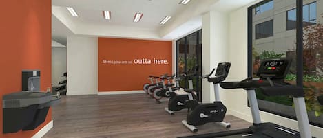 A modern gym with multiple treadmills and exercise bikes, a water dispenser, and a motivational quote on the wall.