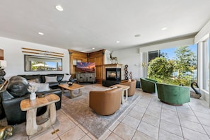 A spacious living area with a fireplace, leather sofas, and a large window offering a view of the outdoors. - Tahoe Keys Easy Lake Access w/ Boat Dock, BBQ (South Lake Tahoe)