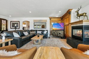 Una sala de estar moderna con chimenea, sofás de cuero, una mesa de centro y un televisor.