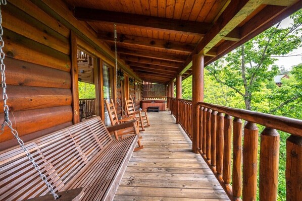 Eine Holzveranda mit Bänken und Geländer mit Blick auf eine grüne Landschaft.