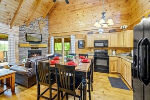 Ein Holzblockhaus-Interieur mit Essbereich, Küche und Kamin.