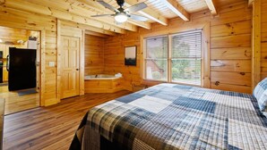Ein Holzblock-Interieur mit einem Bett, einer Badewanne und einem Deckenventilator.