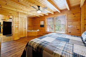 Ein Holzblock-Interieur mit einem Bett, einer Badewanne und einem Deckenventilator.