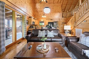A cozy cabin interior with a leather sofa, a dining table with a tray, and a kitchen area in the background. - Scenic Escape Luxury Cabin w/ Views, Hot tub, Golf (Sevierville)