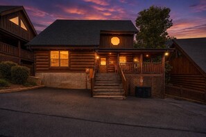 A log cabin with a porch, a staircase, and a large circular window. - Scenic Escape Luxury Cabin w/ Views, Hot tub, Golf (Sevierville)