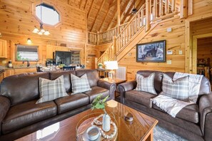 Ein Holzblockhaus-Innenraum mit Wohnzimmer, Küche und Treppe.