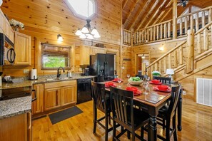 A wooden cabin interior with a kitchen, dining area, and a staircase. - Scenic Escape Luxury Cabin w/ Views, Hot tub, Golf (Sevierville)