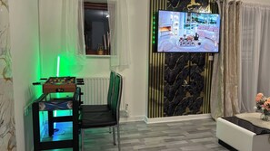 A living room with a foosball table, a television mounted on the wall, and a view of the outdoors through a window.