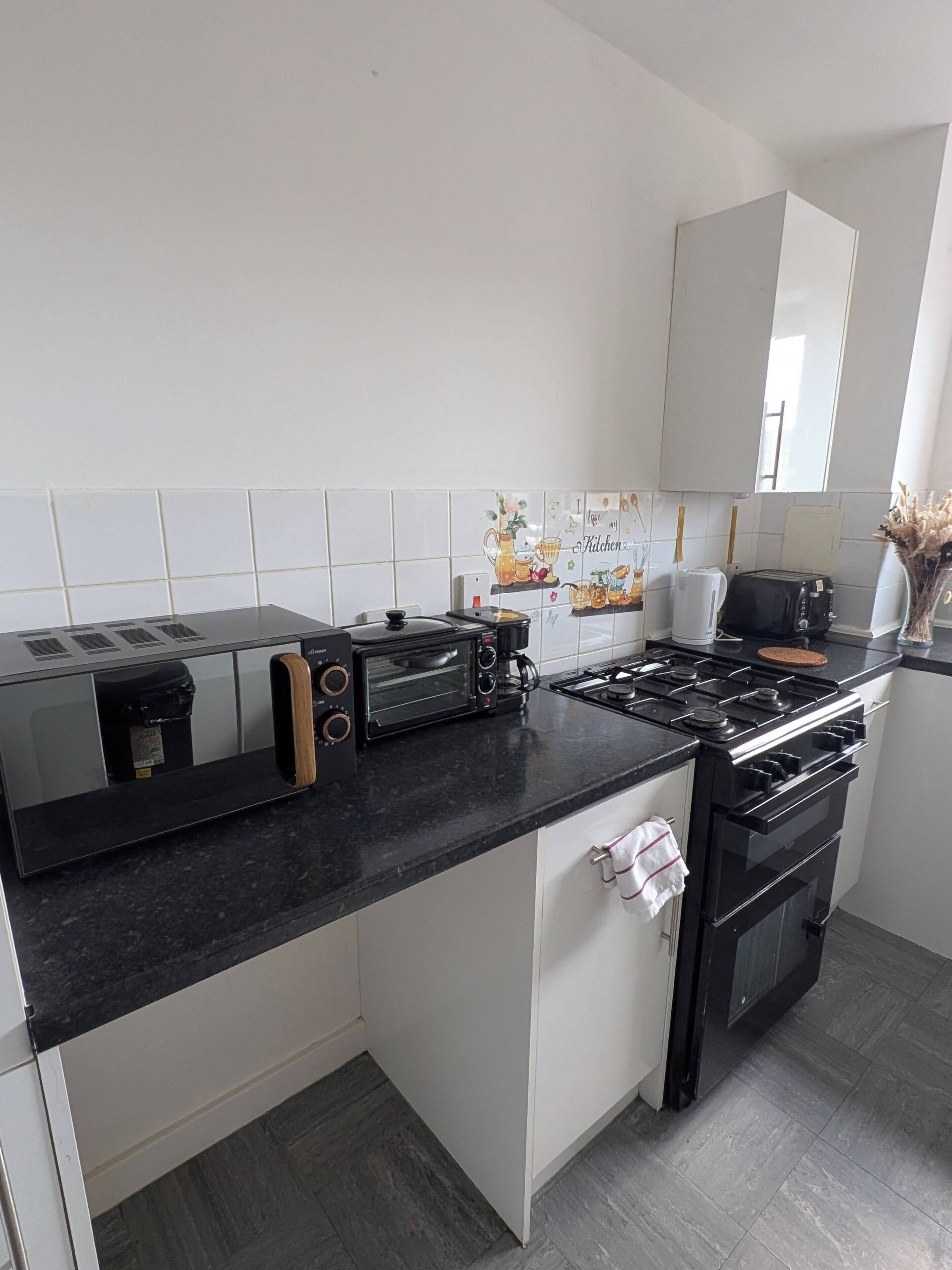 A modern kitchen with a black countertop, a built-in oven, a stove, and a toaster.