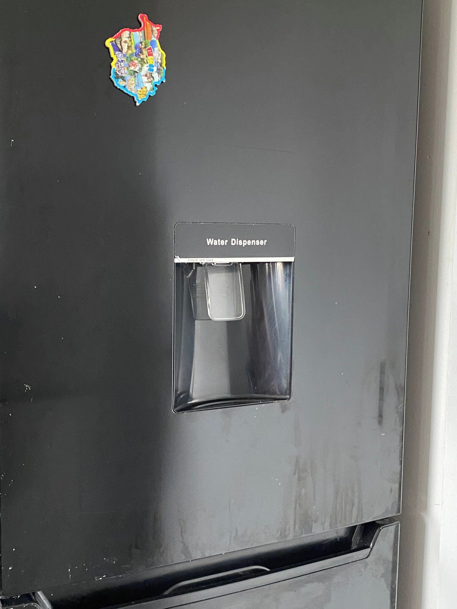 A water dispenser on a black refrigerator.