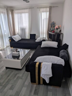 A modern living room with a sectional sofa, a coffee table, and a flat-screen TV on a stand.