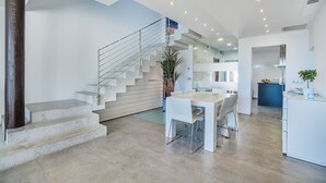 Een modern interieur met een trap, een eethoek en een keuken.