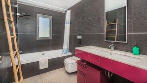 Een moderne badkamer met een badkuip, een wastafel met spiegel, en een toilet.