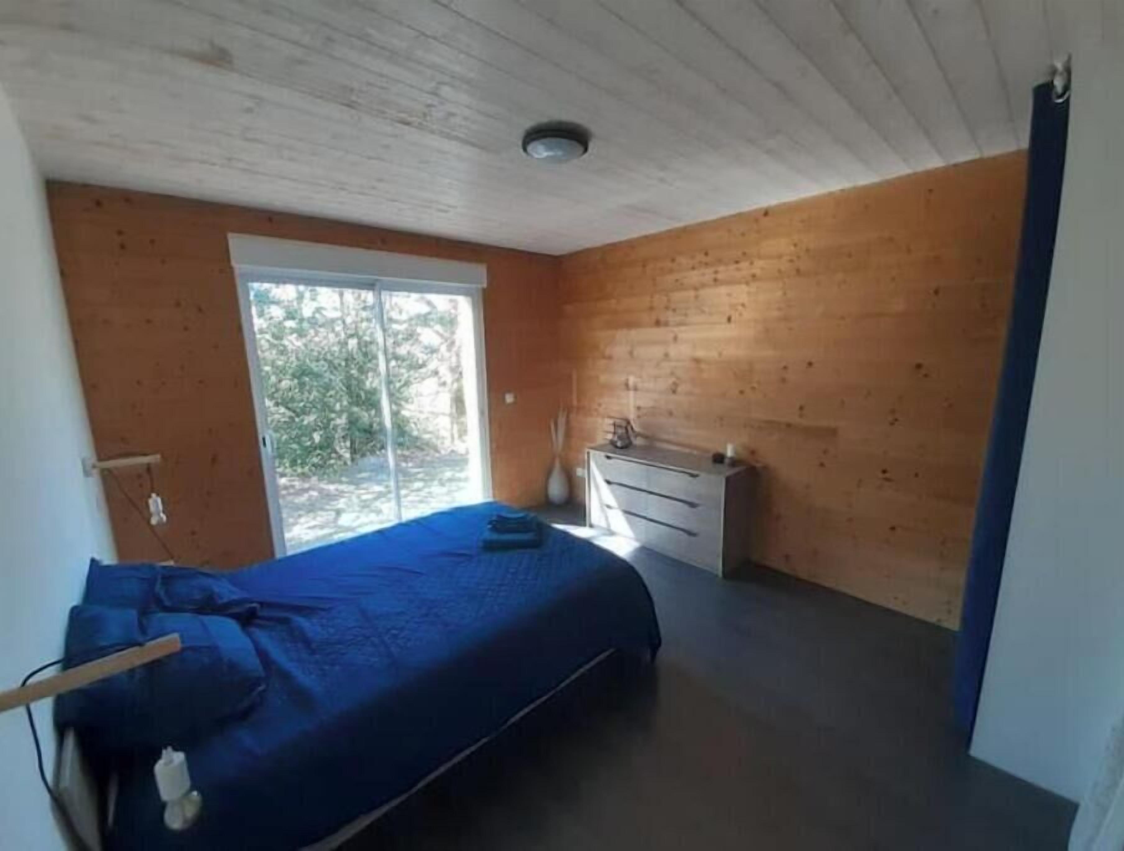 A bedroom with a bed, a dresser, and a window.