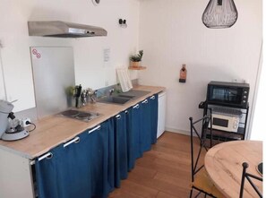 A compact kitchen with a microwave, kettle, and a small sink.