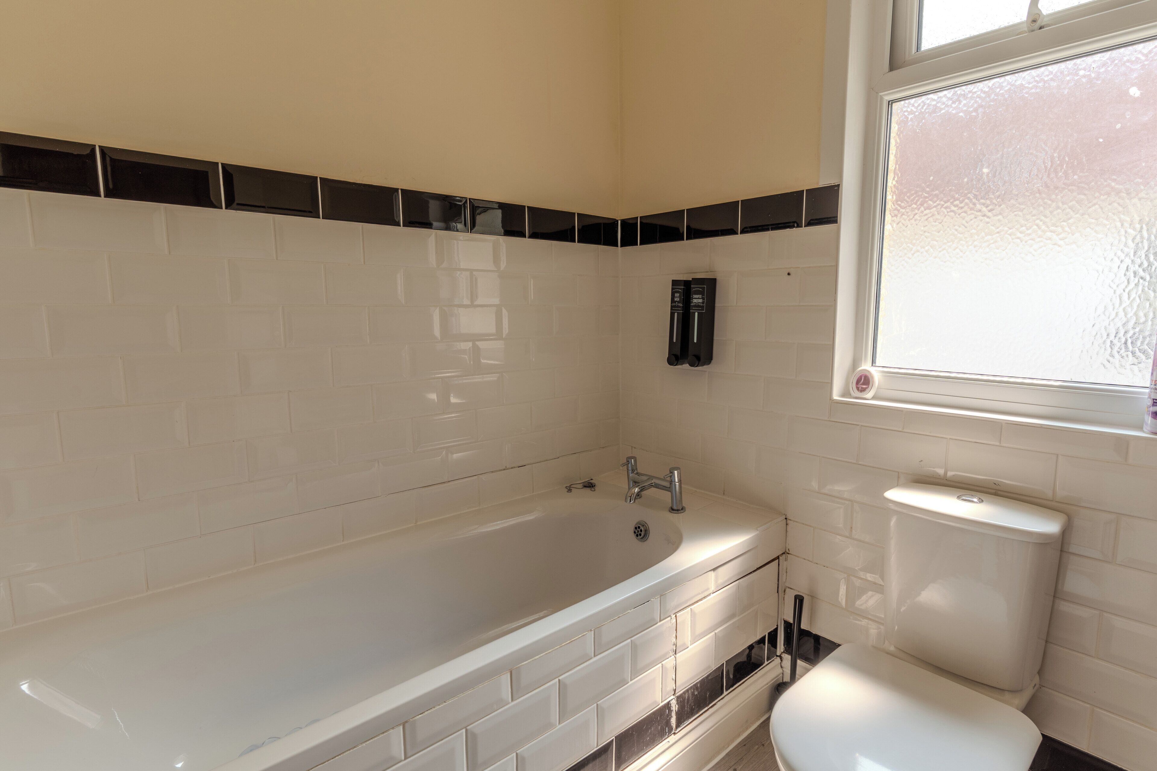 Un baño con bañera, inodoro y ventana.