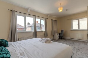 A hotel room with a bed, a desk, a chair, and a view of buildings outside the window.