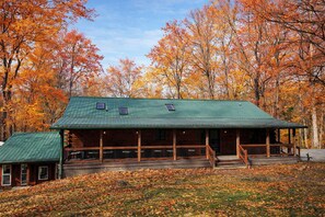 Eine Lodge mit einem grünen Metalldach, Holzfassade und einer Veranda mit Geländern.