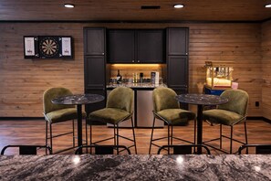A modern kitchen with wooden paneling, a bar area, and a dartboard. - Hocking Hills, Pool, Hottub & Sauna (Logan)
