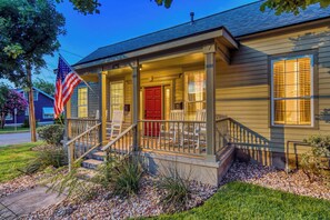A two-story house with a porch, a red door, and an American flag. - Charming 2BR House 1 Block off the Square (Georgetown)