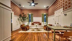 A room with a patterned brick wall, a ceiling fan, a sofa, a coffee table, and a dining table with chairs.
