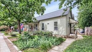 A residential house with a front porch, a small garden, and a flag.