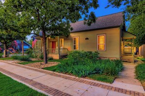 A two-story house with a front porch, a small deck, and a well-maintained garden. - Charming 2BR House 1 Block off the Square (Georgetown)