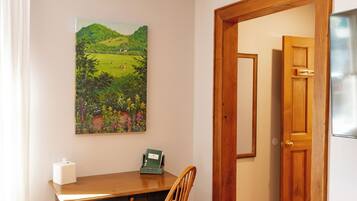 A room with a wooden dining table, a chair, a painting on the wall, and a door leading to another room.