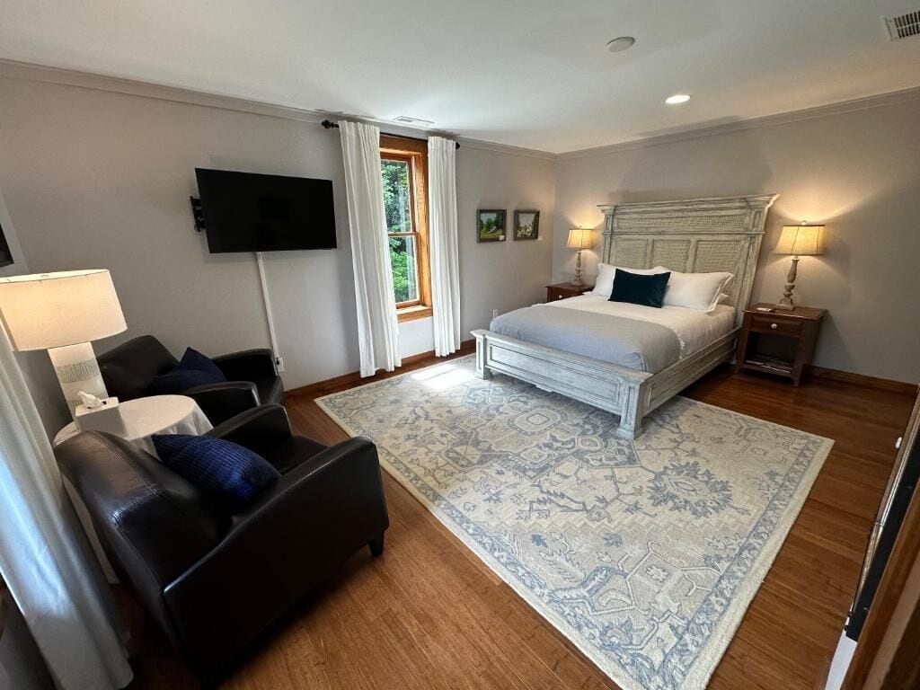 Un dormitorio con cama, sofá, televisión y ventana.