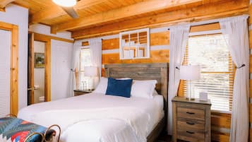 Un dormitorio con paneles de madera, una cama grande, mesitas de noche y una ventana con cortinas.