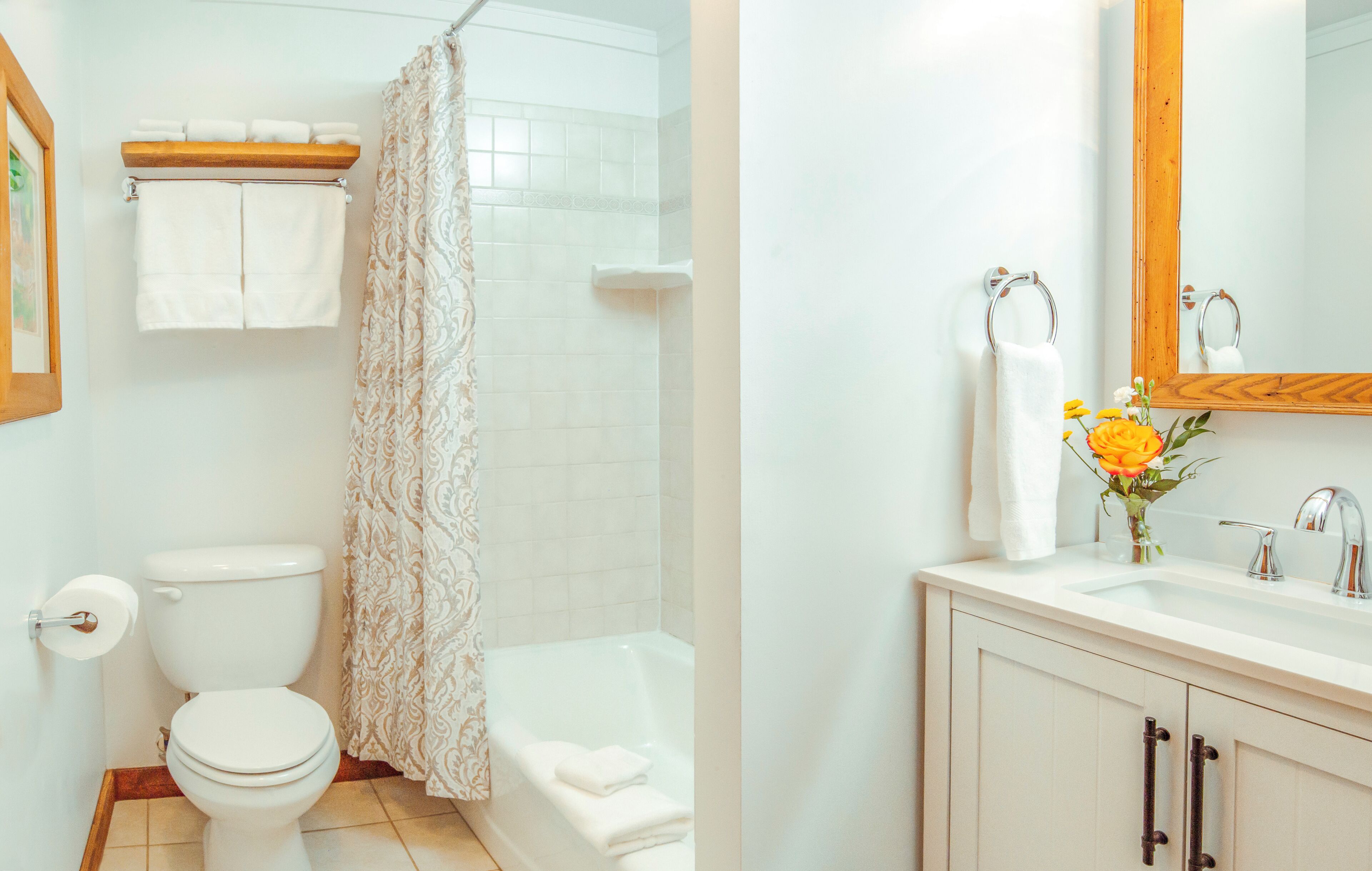 A bathroom with a toilet, a shower, and a sink with a mirror.
