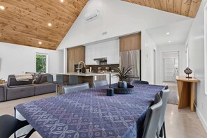 A modern kitchen with a built-in oven, a dining area with a table and chairs, and a living room with a sofa and a coffee table.