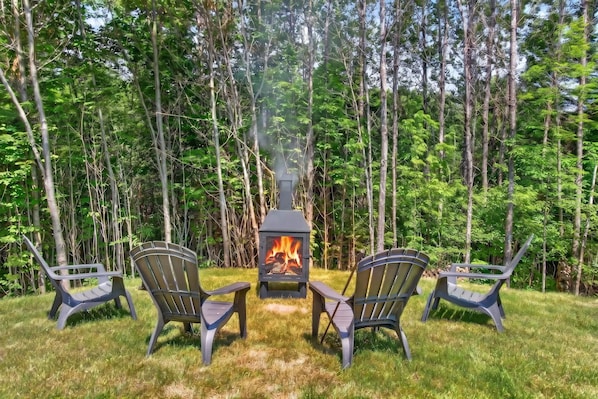 An outdoor seating area with three chairs and a central wood-burning stove.