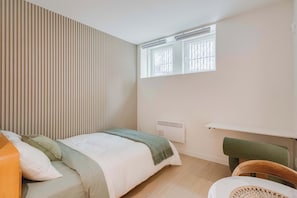 A bedroom with a bed, a chair, a radiator, and a window. - 002 Cook - Loft in the Heart of Old Quebec (Québec)