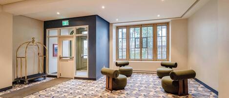 A hotel lobby with a patterned floor, a reception desk, and a large window with a view.